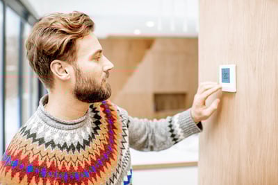 homme-pull-regle-thermostat-chauffage-ambiance-logement