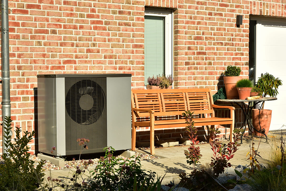 maison-pompe-chaleur-unite-exterieur-soleil-terrasse-banc-mur-briques-1