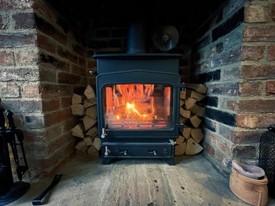 poele-bois-buches-cheminee-parquet-maison-flammes-mur-briques